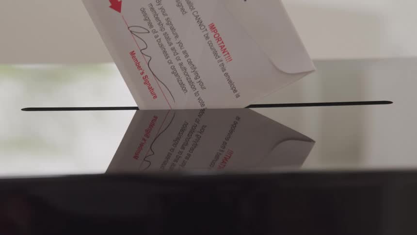 An envelope is being slid into a mail slot