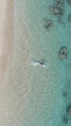 Aerial view of a person with a surfboard entering the sea
