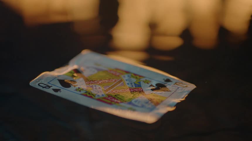 Queen of spades playing card floating on a body of water