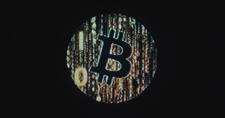 The orange BTC logo or icon displayed as a matrix style animation consisting of binary digits 0 and 1 fades in and out on a pixelated computer monitor or screen creating digital pixel art motion graphic out of the cryptocurrency
