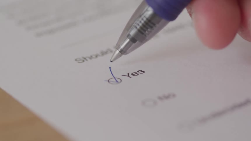 Close up of a person ticking an option on an answer sheet