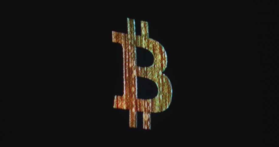 The letter B from the Bitcoin or BTC logo appears and dissolves on a black pc monitor with RGB pixel panel as symbol for the new digital asset class and the digitalization of the new financial system of the future based on blockchain technology