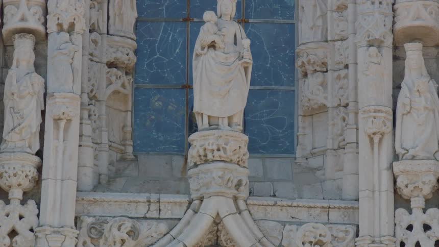A statue stands in front of a window on a cathedral