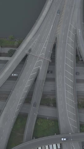 An aerial view showcases a complex multilane highway interchange with numerous vehicles navigating the roads bordered by water and green spaces