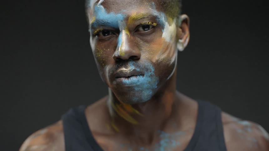 A man with face paint turns slowly