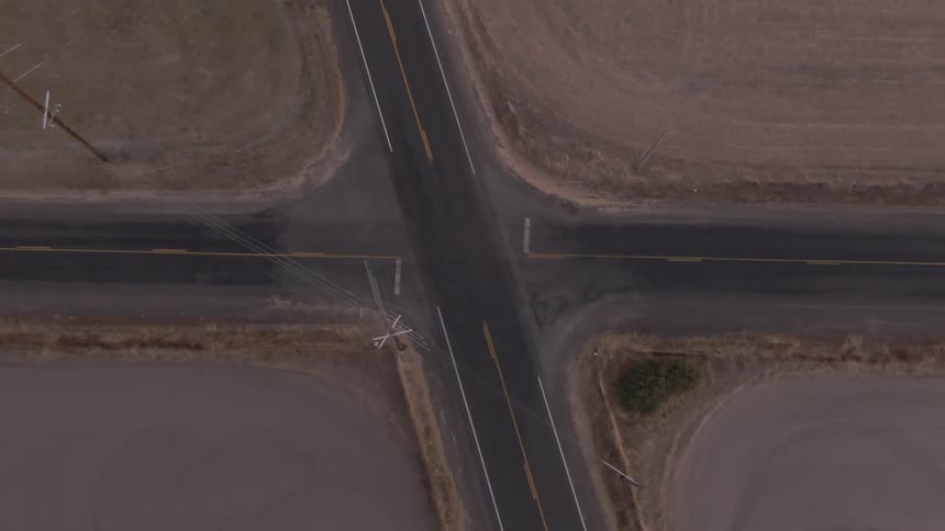 Aerial view of a rural road intersection surrounded by empty or fallow fields