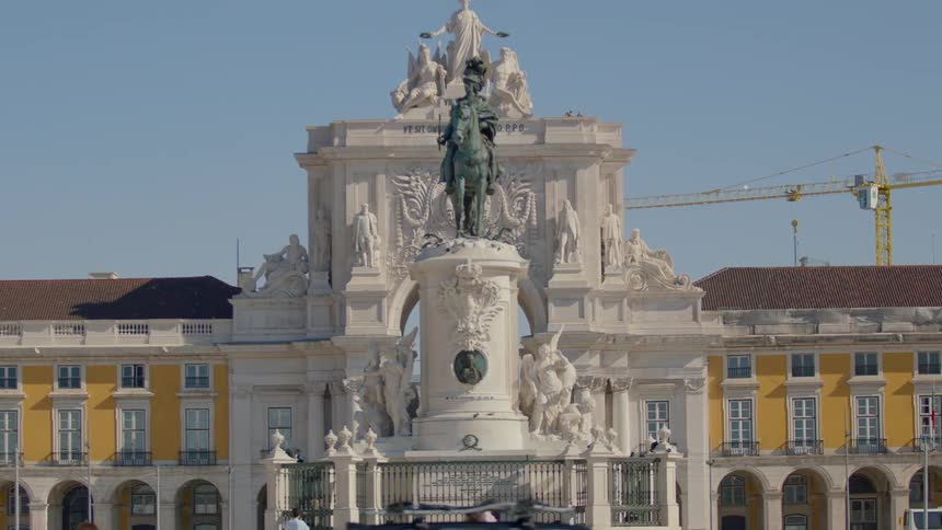 Pedestrians and vehicles surround a statue in a city