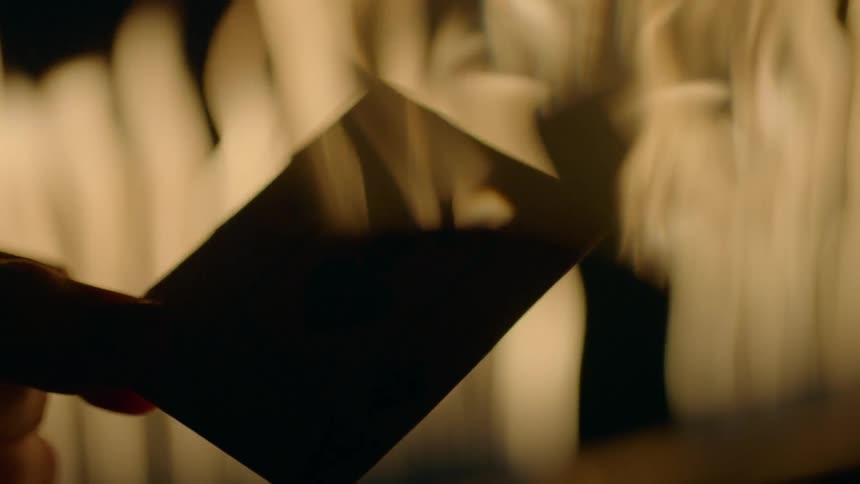 A hand holds a card with flames burning in the background