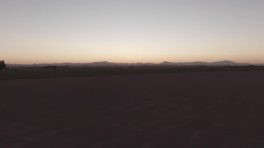 Landscape of a desert field with mountains on the horizon at dawn