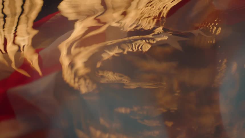 An american flag is underwater with fire above
