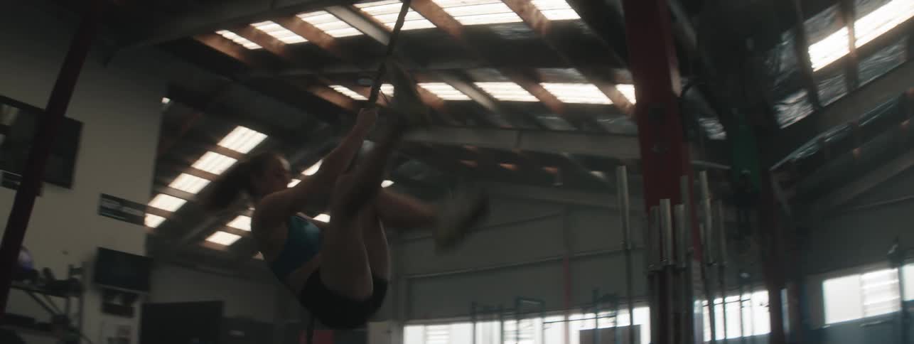 A woman in a crossfit gym performing a rope climbing exercise