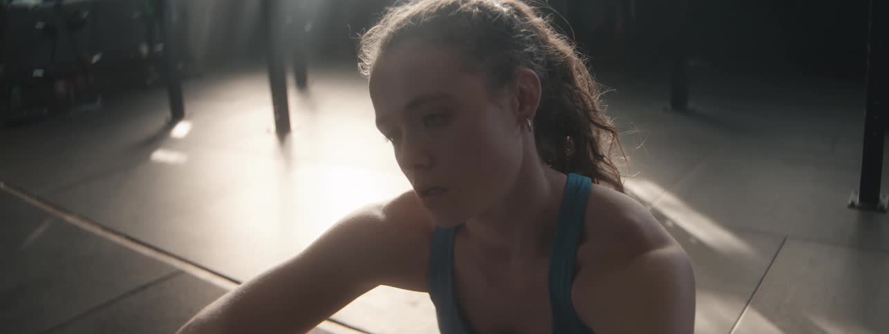 A woman sits on the floor of a gym