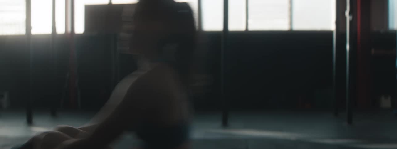 A woman exercises while using a rowing machine in a gym space
