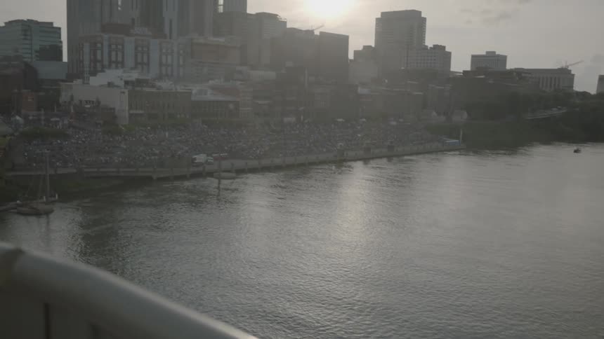 Water flows as the sun reflects off it next to city buildings