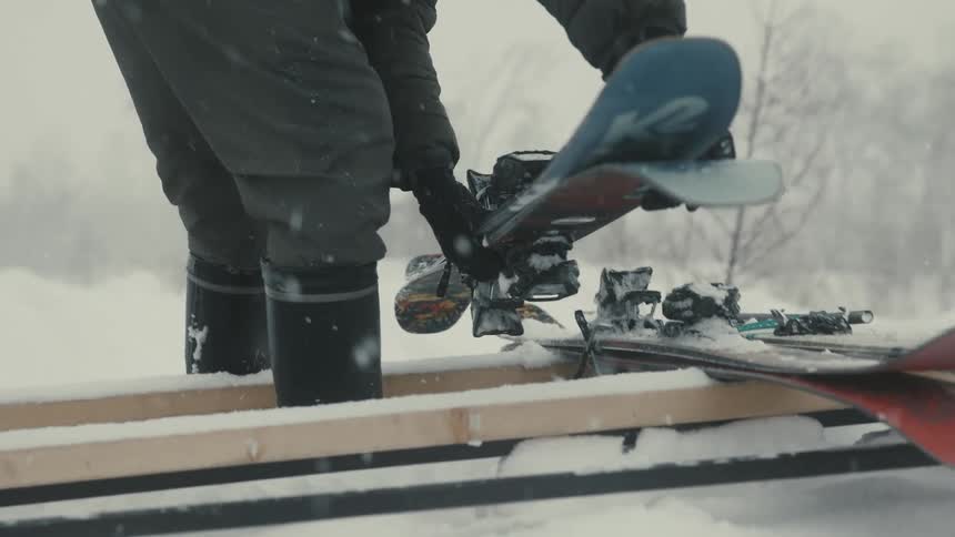 Person places sets of skis on a wooden frame on a snowy winter day