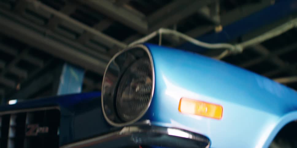 Blue car stands parked under a structure with a high ceiling