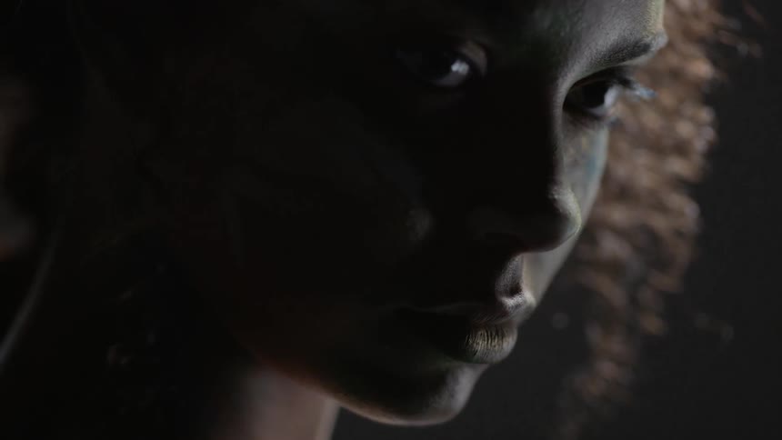 A woman with paint on her face turn her head to face forward