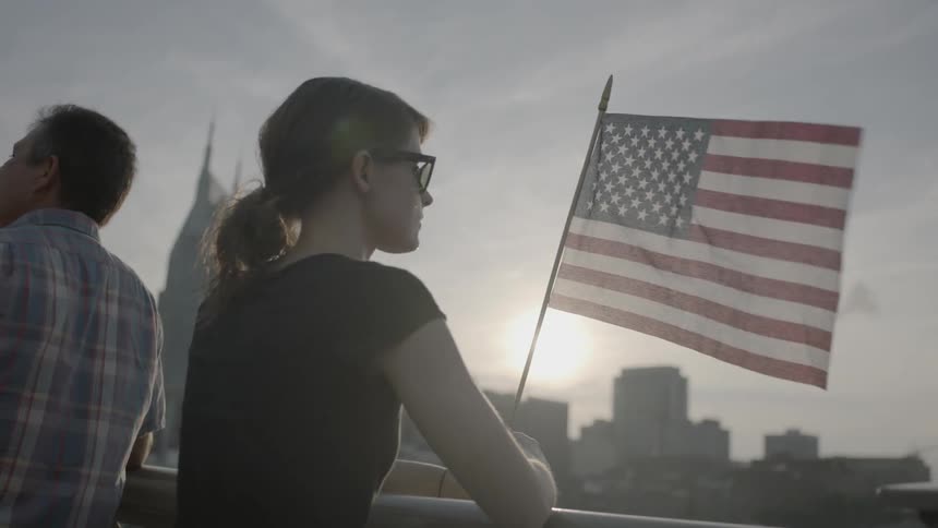 People sit and watch over a city by a flag