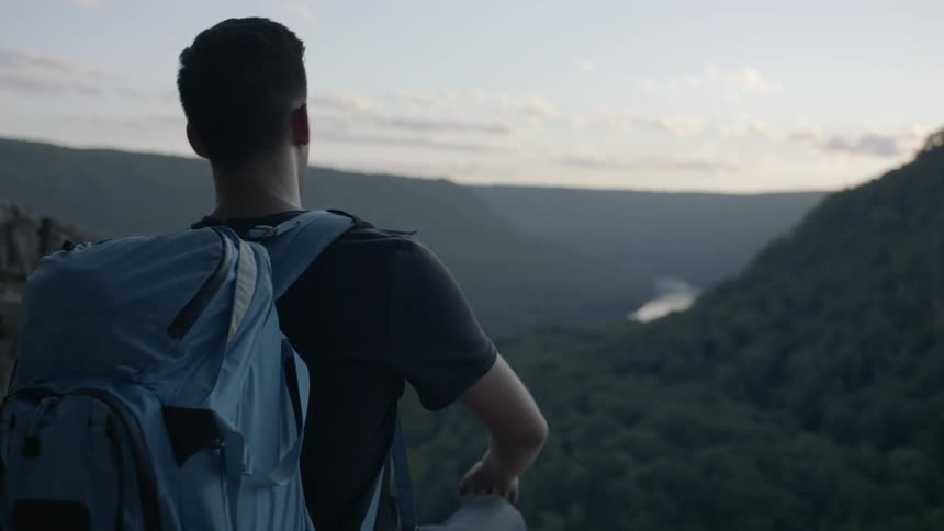 A hiker sits down atop a mountain while carrying a backpack