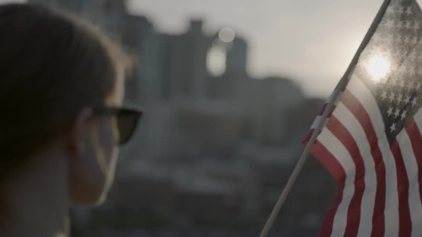 A woman holds an american flag on a sunny day