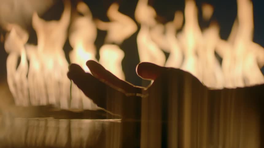 A hand rises out of water with flames in the background