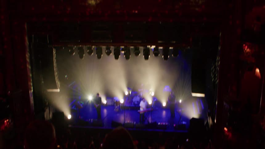 Person records video with their smartphone while attending a band concert in a brightly colored theater
