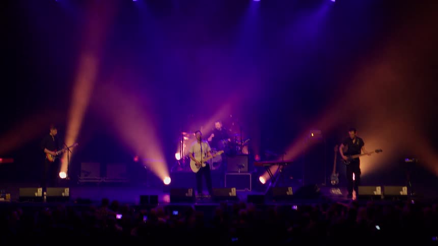 A band performs on the stage in front of a large crowd
