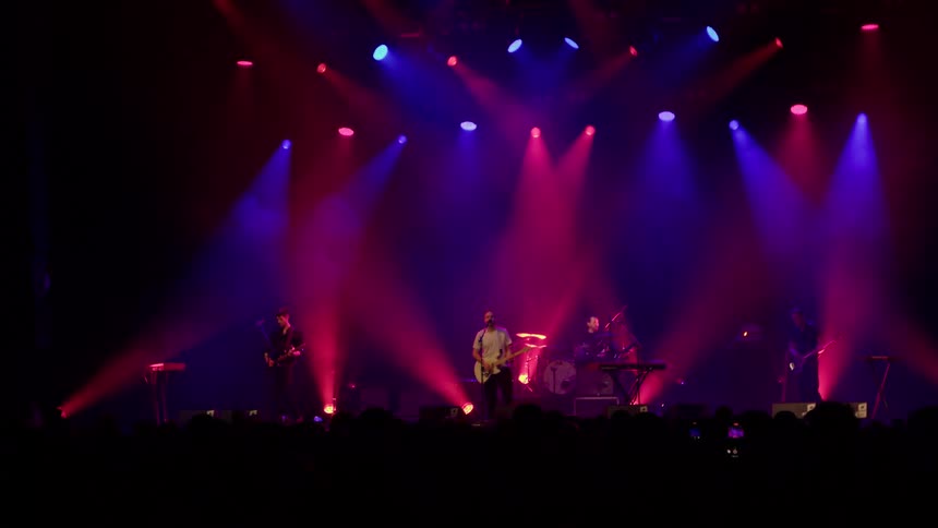 A rock band performing on stage for a large audience