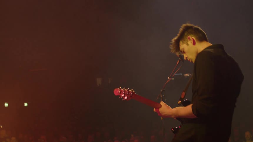 The guitarist moves around the stage while playing