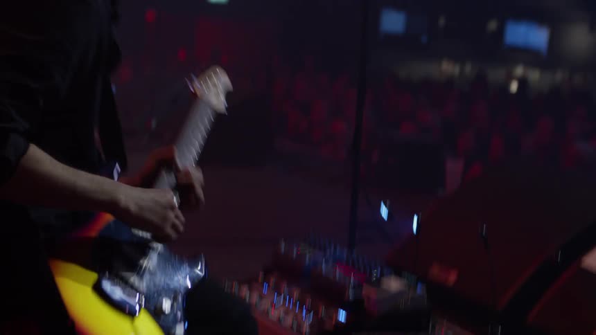 Guitarist in a rock band kneels during a performance at a concert