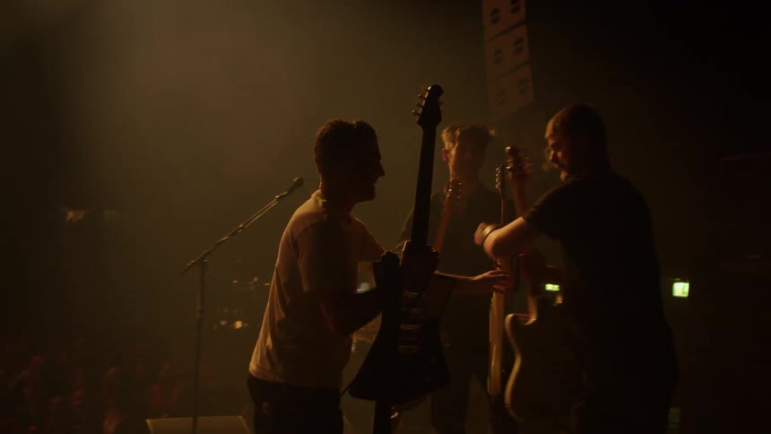 A musician switches guitars during a performance