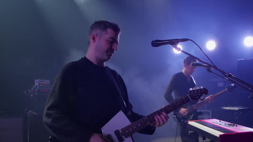 A guitarist performs on stage with a band during a live concert