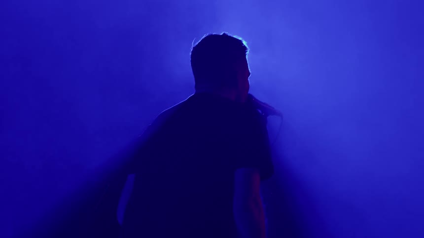 A man on stage singing into a microphone at a concert