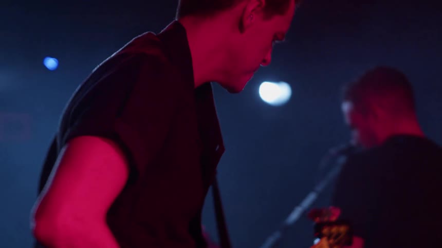 Man playing guitar in a band performing for a crowd of people