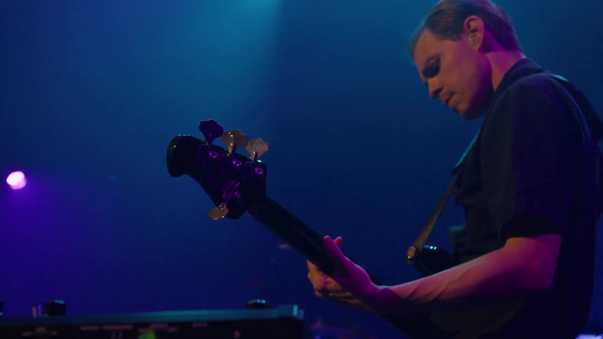 A man strums the guitar strings on a concert stage during a live performance