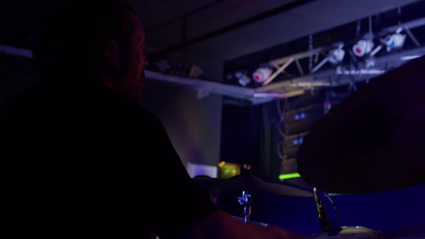The man is happy as he plays the drums on stage