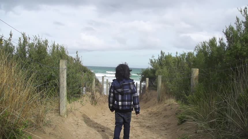 Child walks towards the ocean