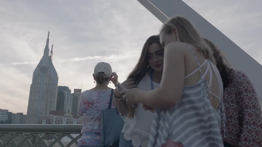 Three women huddle around a phone
