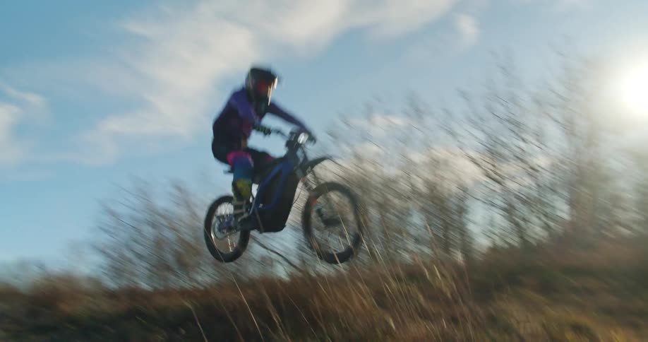 Motocross rider jumps on a dirt bike over grassy trail