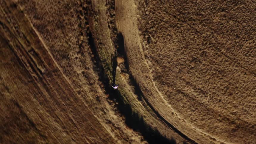 Man speeds through trail in field on dirtbike