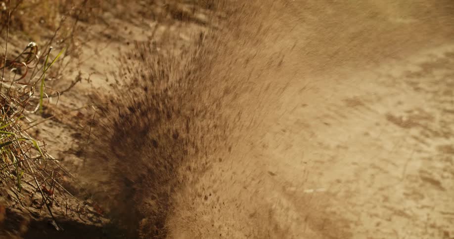 The dirt bike throws dirt as it makes a sharp turn