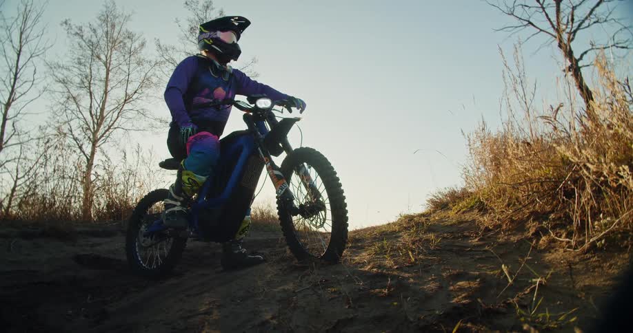Person in helmet sitting on motorcycle on outdoor trail