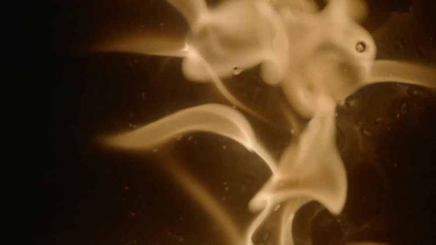 A fire begins to flare in a dark area