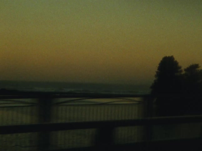 A vehicle drives across a bridge in the evening