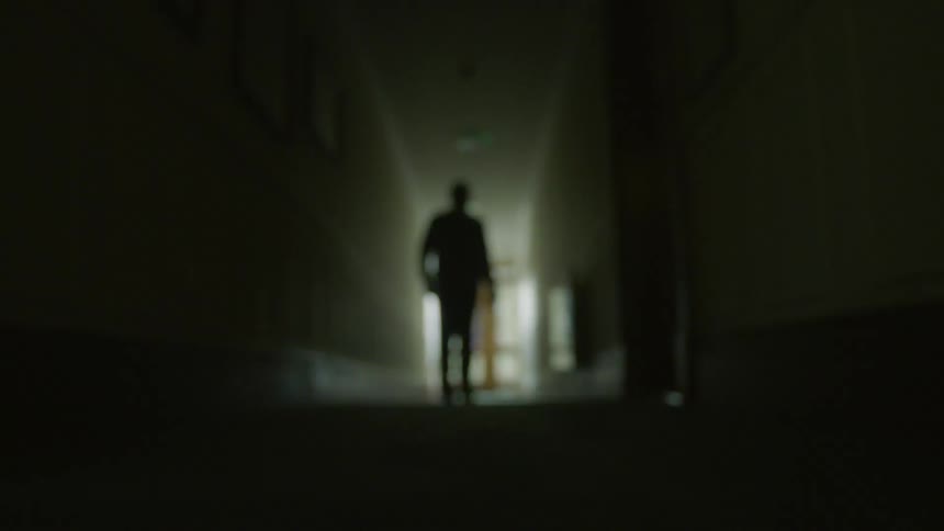 The hall is dark and a person walks down it