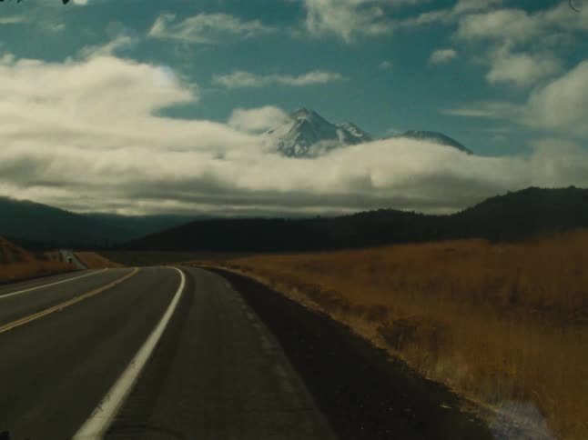 A mountain range sits in the distance beyond a road