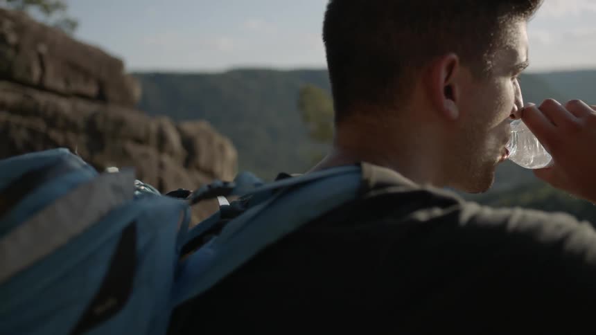 A man drinks water while hiking in the mountains