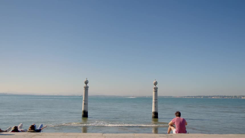 A man is sitting by the water on a sunny day