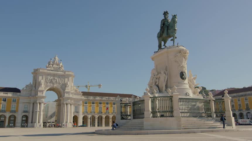 People rest at the base of a statue in a plaza