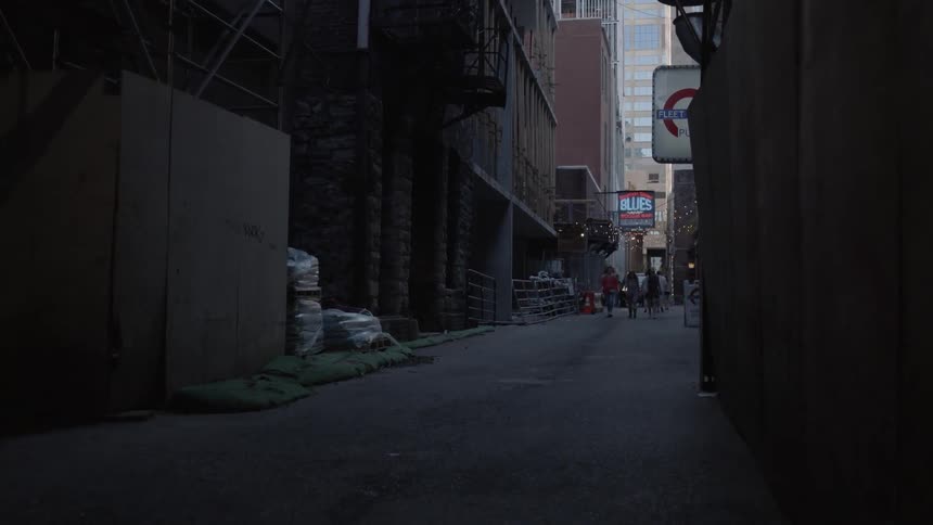 A group of people holding a flashlight walk towards an alley